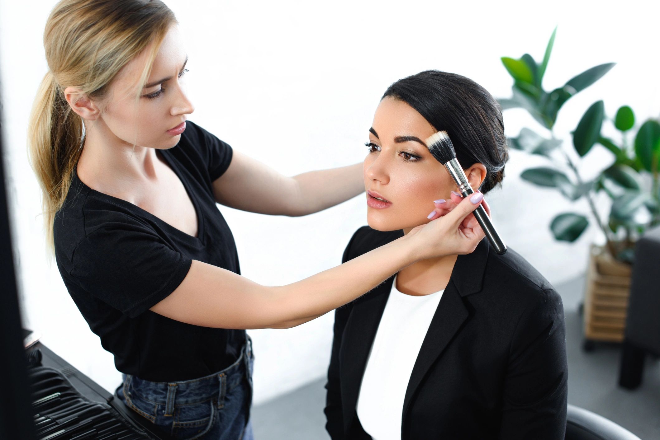 Makeup artist applying eyeshadow to client in bright salon